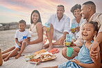 Closeup of a mixed race family having a picnic on the beach and smiling while having some food with snacks. Happy family bonding on a day out at the beach