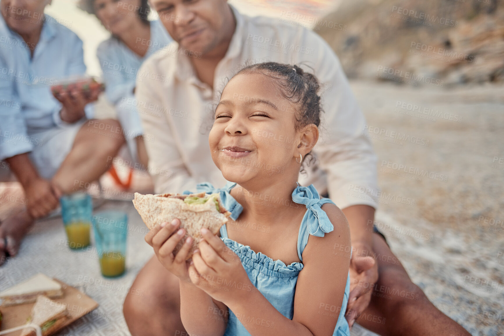 Buy stock photo Picnic, child and smile on beach with sandwich, happiness and excited with family. Kid, wellness and food in nature for nutrition, favorite snack and lunch on outing for travel and fun in Brazil