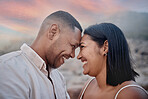 Closeup of an young affectionate mixed race couple standing on the beach and smiling during sunset outdoors. Hispanic couple showing love and affection on a romantic date at the beach