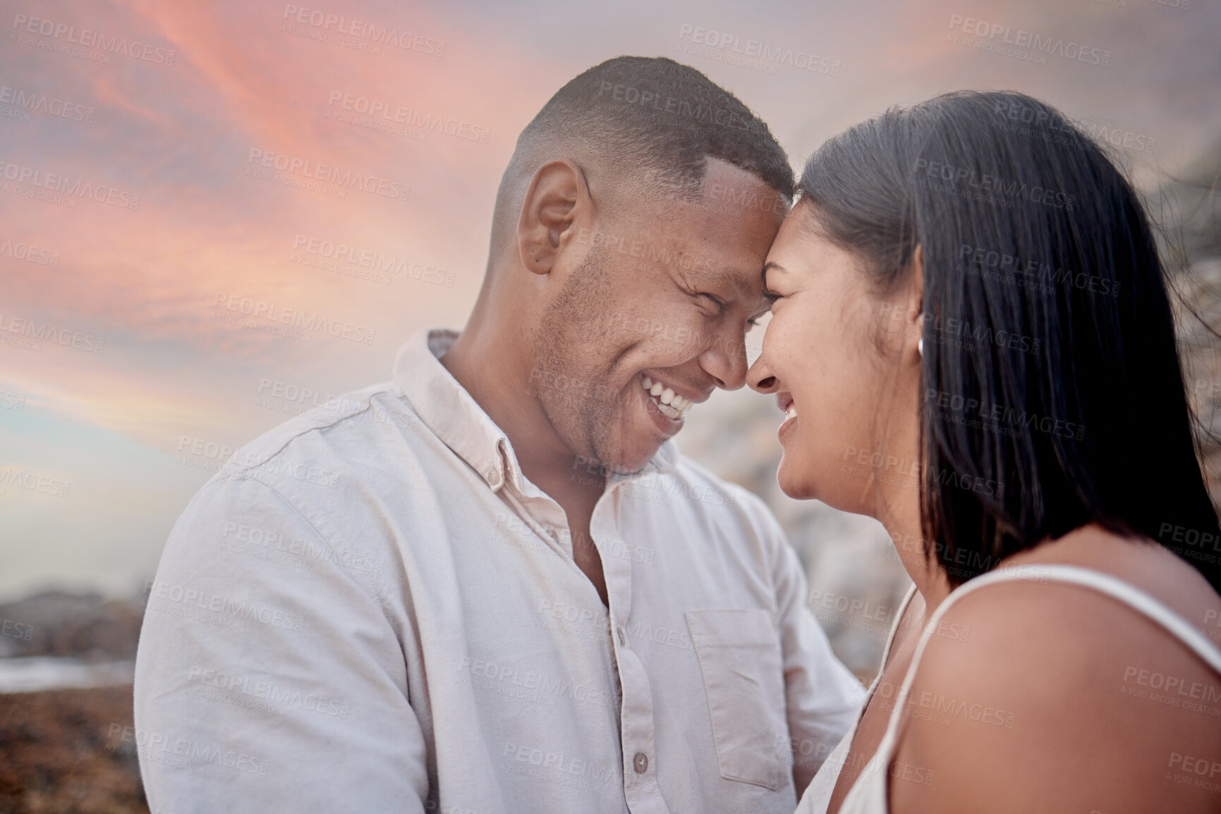 Buy stock photo Happy, connection and couple on beach at sunset on romantic date for travel with vacation or weekend trip. Smile, care and young man and woman bonding by ocean in evening on tropical holiday.