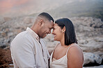 Closeup of an young affectionate mixed race couple standing on the beach and smiling during sunset outdoors. Hispanic couple showing love and affection on a romantic date at the beach