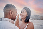 Closeup of an young affectionate mixed race couple standing on the beach and smiling during sunset outdoors. Hispanic couple showing love and affection on a romantic date at the beach