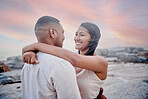 Closeup of an young affectionate mixed race couple standing on the beach and smiling during sunset outdoors. Hispanic couple showing love and affection on a romantic date at the beach