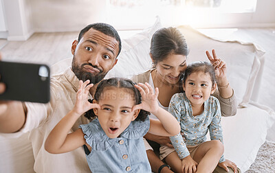 Buy stock photo Funny face, love and selfie with family on sofa in living room of home together for bonding or humor. Bunny ears, happy or relax with mom, dad and sibling girl children in apartment for photograph