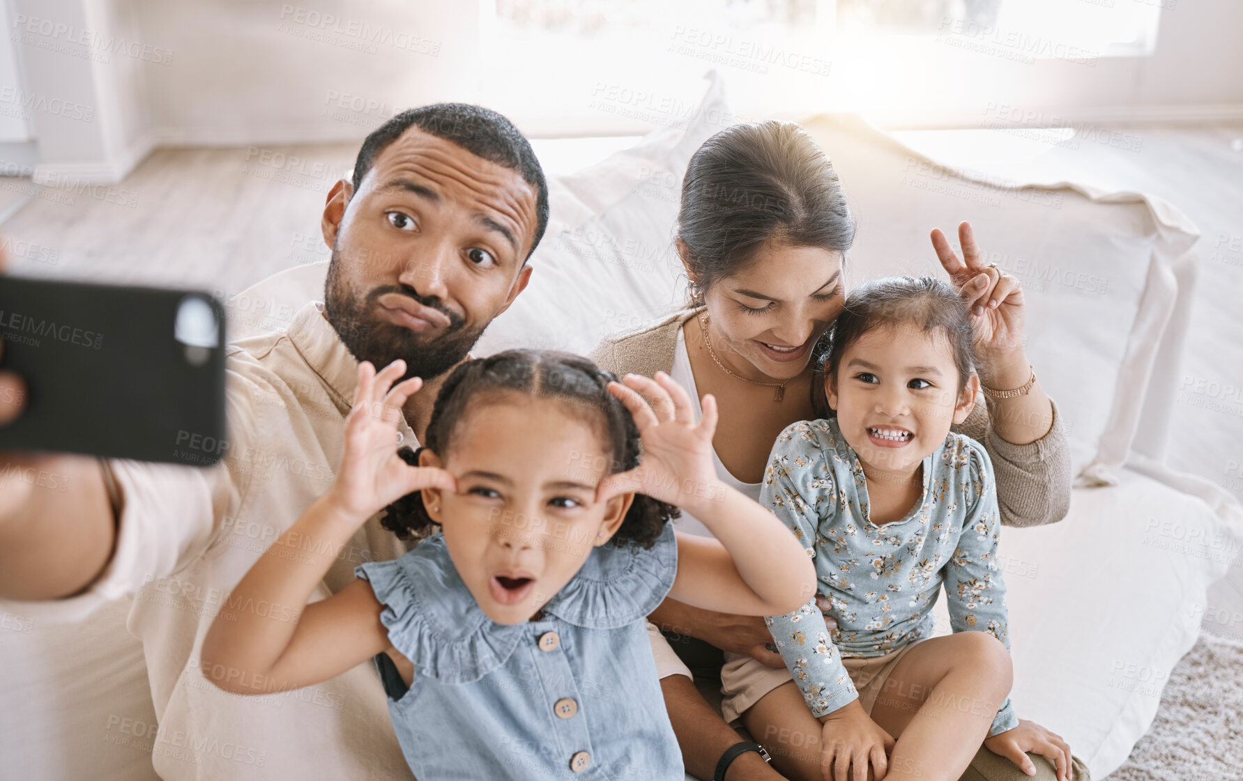 Buy stock photo Funny face, love and selfie with family on sofa in living room of home together for bonding or humor. Bunny ears, happy or relax with mom, dad and sibling girl children in apartment for photograph