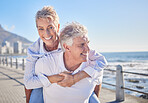 A happy mature caucasian couple enjoying fresh air on vacation at the beach. Smiling retired couple getting a cardio workout while being playful and having fun together on a romantic date