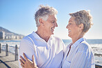 A happy mature caucasian couple enjoying fresh air on vacation at the beach. Smiling retired couple hugging and embracing while bonding outside together