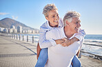 A happy mature caucasian couple enjoying fresh air on vacation at the beach. Smiling retired couple getting a cardio workout while being playful and having fun together on a romantic date