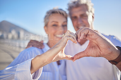 Buy stock photo Heart, happy and mature couple in beach, hug and bonding in vacation for fresh air, smile and nature. Holiday, old man and woman for romance in Australia, travel and date in ocean, enjoy and weekend