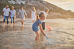 Multi generation family holding hands and walking along the beach together. Caucasian family with two children, two parents and grandparents enjoying summer vacation while kids use nets in the water