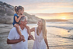 Closeup of a little caucasian girl being carried by her grandpa while her mother walks on the beach during sunset.  Family fun in the summer sun