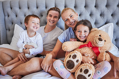 Buy stock photo Portrait, smile and family with hug in bedroom for love, bonding and weekend support of childhood memory. Happy, parents and kids with teddy bear, embrace and relax together for morning care at house