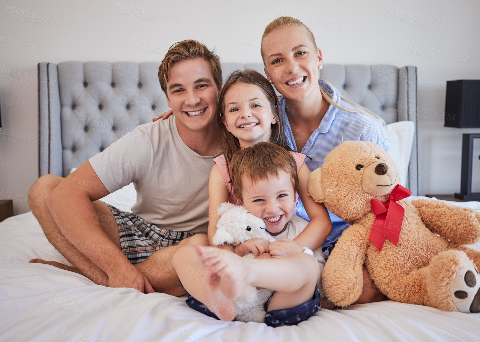 Buy stock photo Portrait, smile and family with embrace in bedroom for love, bonding and support of childhood memory. Happy, parents and girl with teddy bear, hug  and connection for relax together or care at house