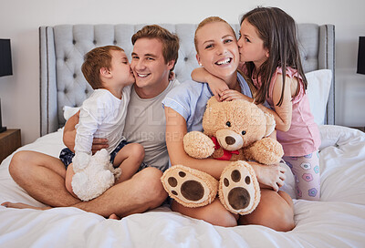 Buy stock photo Happy, family and embrace with kiss in bedroom for love, bonding and childhood support of memory. Smile, parents and kids with teddy bear, hug and relax together for relationship connection at house