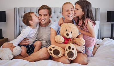 Buy stock photo Smile, family and embrace with kiss in bedroom for love, bonding and childhood support of memory. Happy, parents and kids with teddy bear, hug and relax together for relationship connection at house