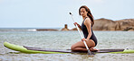 Surfer, fitness and woman in ocean with surfboard and paddle, swimwear and focus with sport outdoor and nature. Beach, exercise and young female surfing, waves and adventure with extreme sports