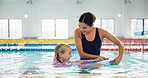 Instructor, helping and child in pool, swimming or woman with smile, proud or teaching girl in water. Bathing suit, happy or learning with teacher in school for training of kid, sports or competition