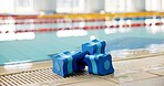 Fitness, indoor sport or dumbbell at swimming pool for safety, learning or aqua aerobics. Blue equipment, water or sponge weights at poolside for muscle therapy, growth or float in wellness center