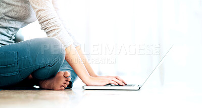 Buy stock photo Cropped image of a young woman sitting on the floor and browsing her laptop