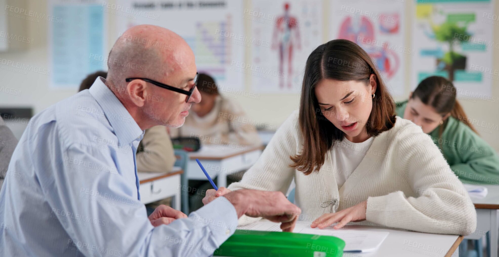 Buy stock photo Man, teacher and girl at desk for education, question and help with information in classroom. Male tutor, student and discussion at table for shared knowledge, life science lesson and assistance