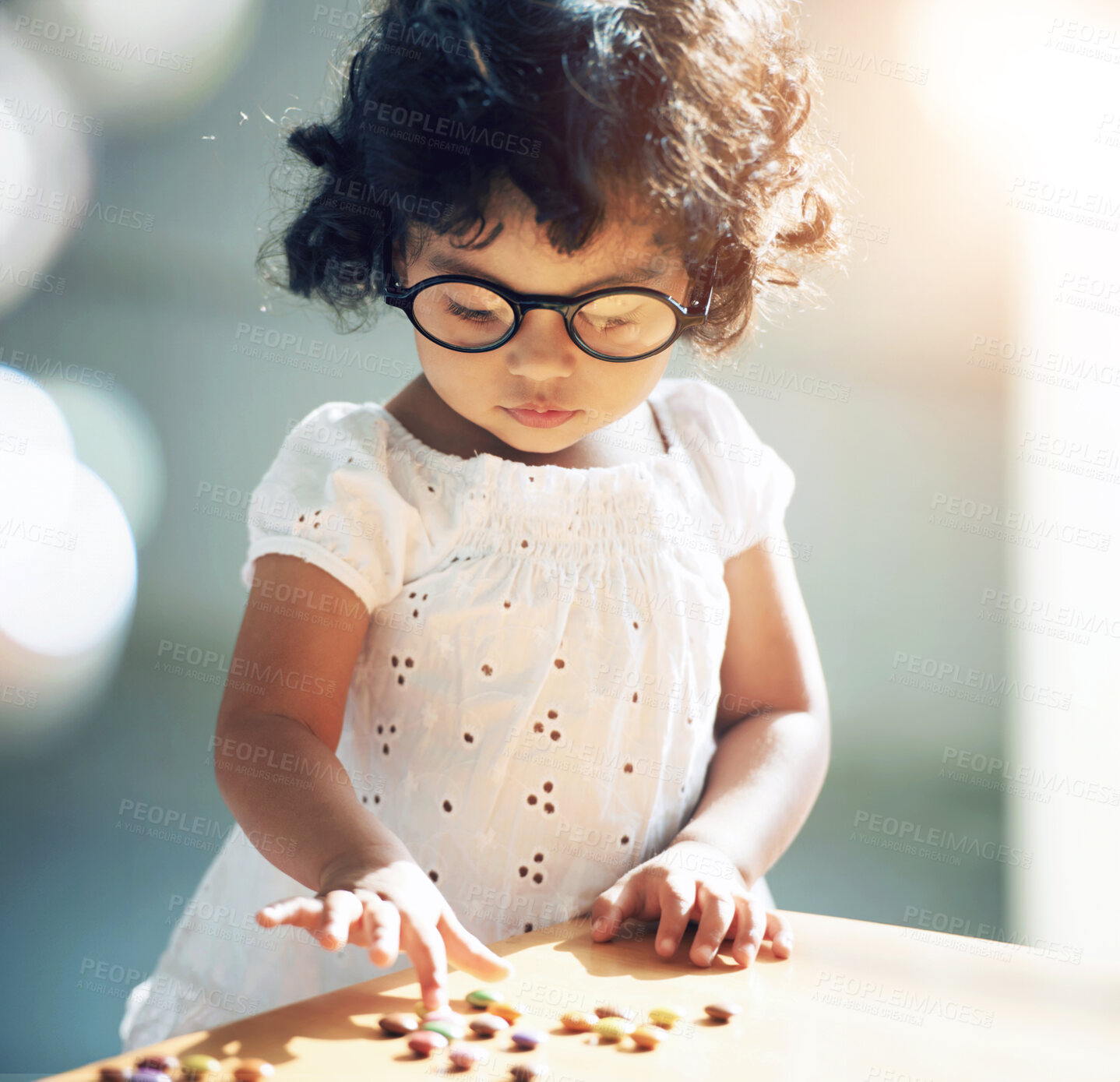 Buy stock photo Shot of a little girl at home alone with pills on the table in front of her