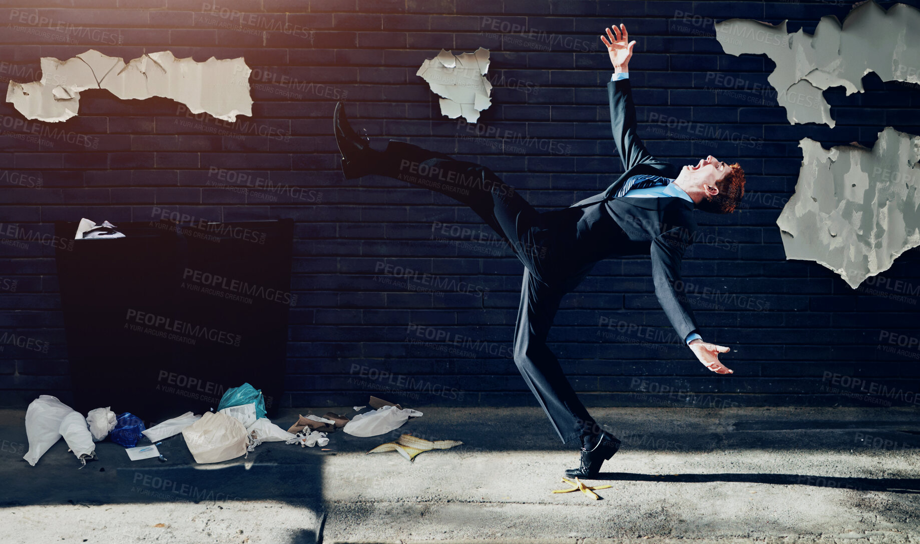 Buy stock photo A young businessman tripping on a banana peel