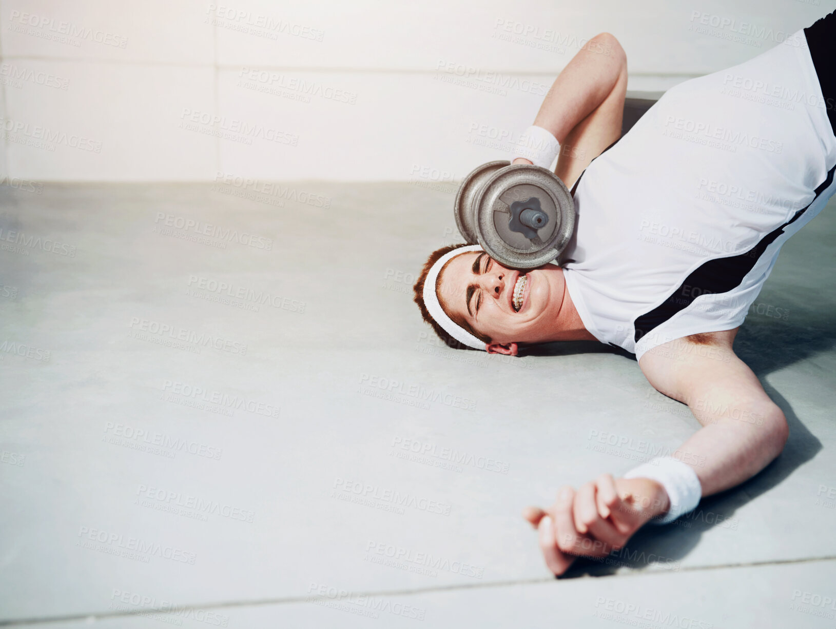 Buy stock photo A young man trying to lift some heavy weights at the gym and getting squashed by a dumbbell