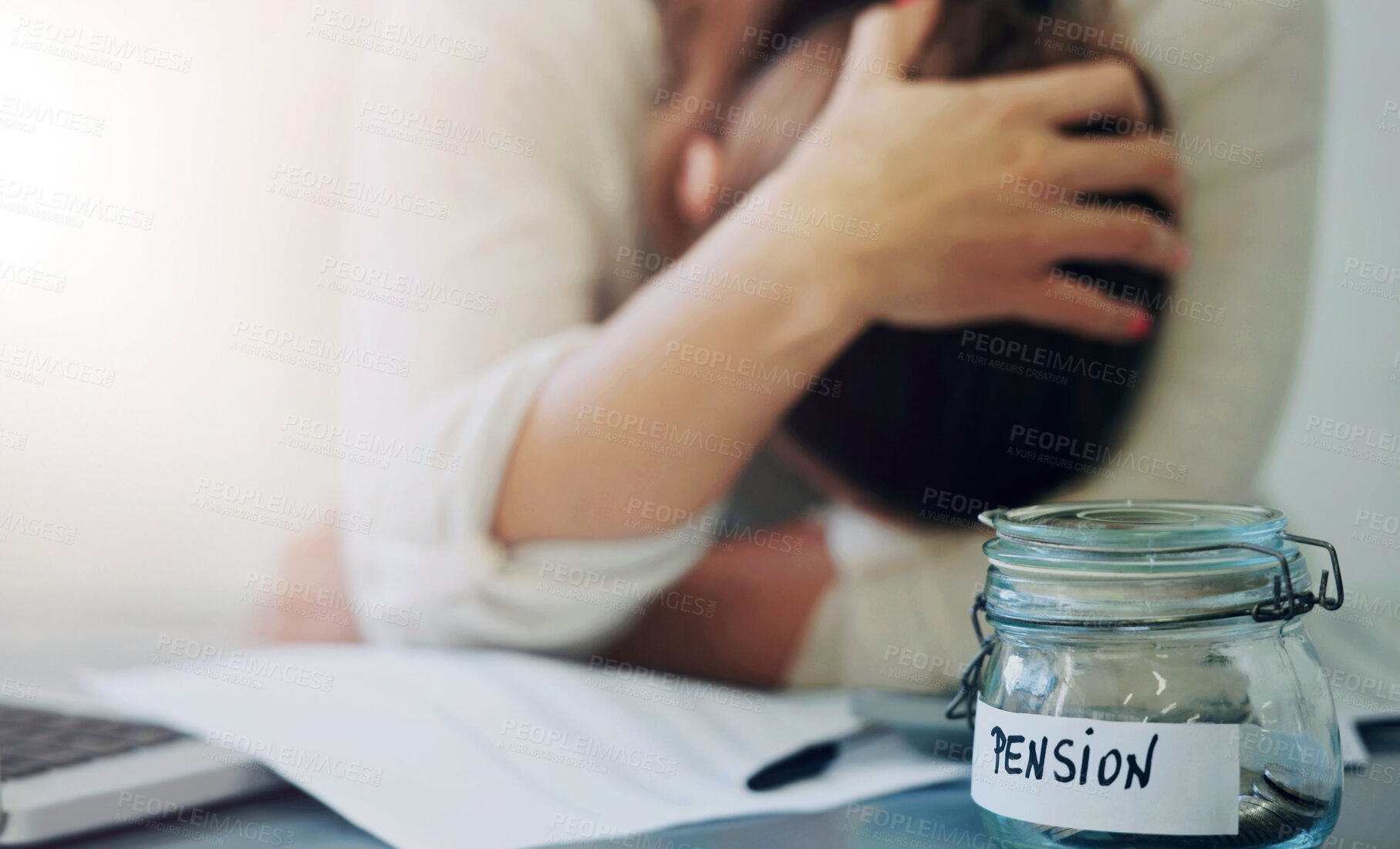 Buy stock photo An upset woman holding her head with a jar of pennies on her desk