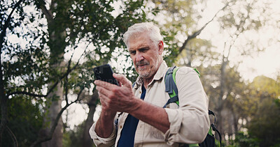 Buy stock photo Hiking, phone and mature man in nature for directions, navigation app and checking route. Lost, low signal and male person in woods with mobile, connectivity and location tracking error in wilderness