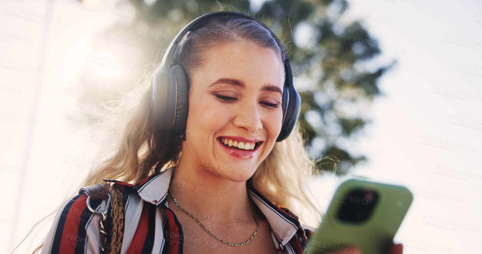 Buy stock photo Woman, phone and headphones outdoor for music, communication and social media with smile and streaming. Female person, smartphone and walking in city for networking, travel and mobile app with radio