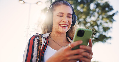 Buy stock photo Girl, phone and headphones outdoor for music, communication and social media with smile and streaming. Female person, smartphone and walking in city for networking, travel and mobile app with radio