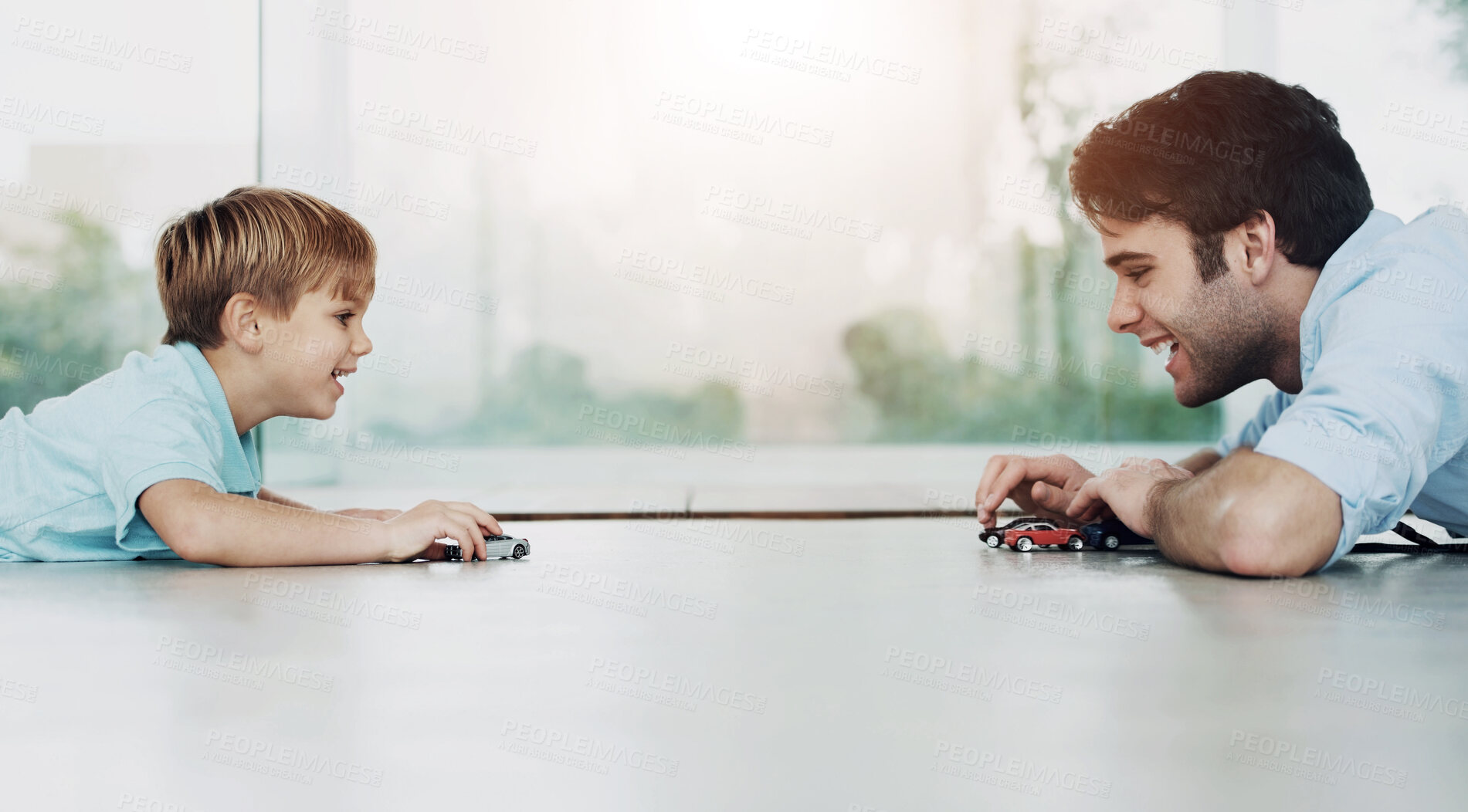 Buy stock photo A cute boy and his young father playing with toy cars on the floor