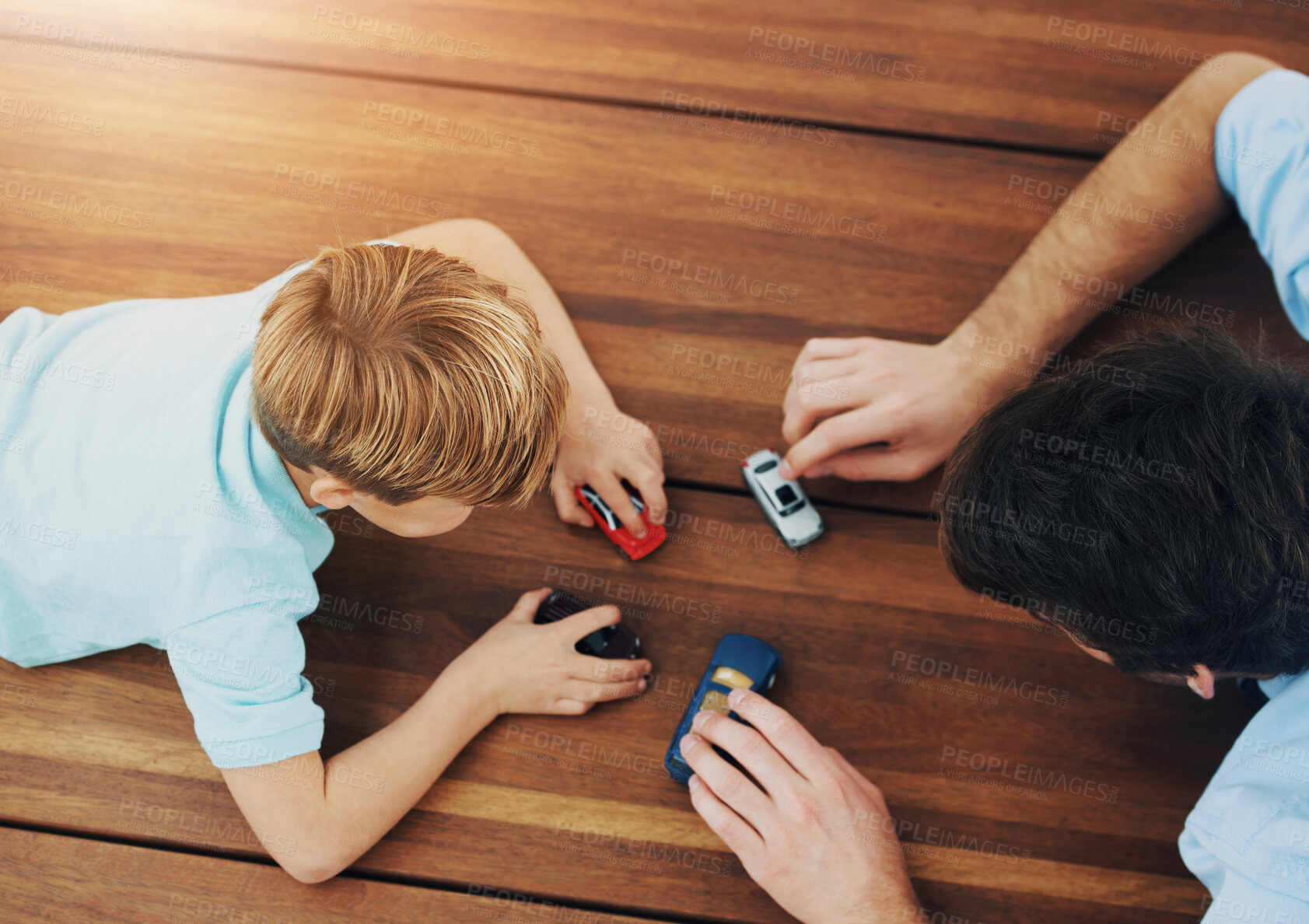 Buy stock photo Overhead view of a father and his son playing with toy cars on the floor