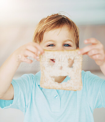 Buy stock photo Shot of a little boy holding up a slice of bread with a cut out smiley face