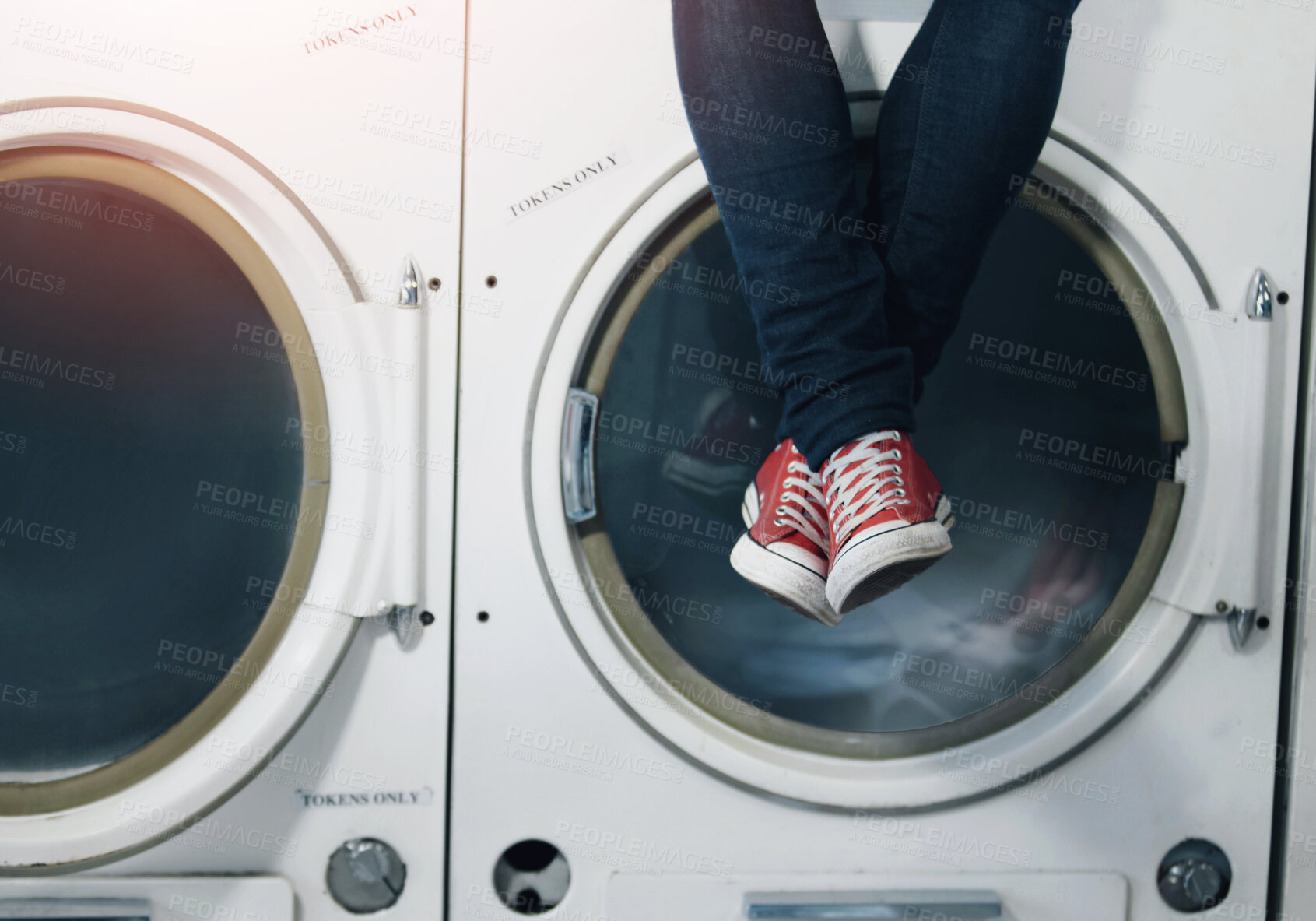 Buy stock photo Cropped image a man's legs as he sits on a washing machine at the laundromat