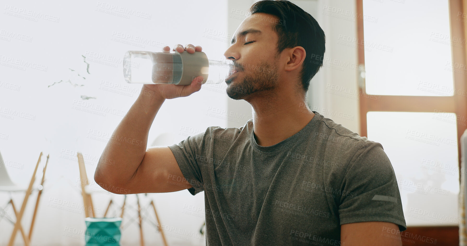 Buy stock photo Man, drinking water and rest in home for yoga, hydration or refreshment for healthy body. Fitness, person and thirsty in living room with bottle, detox and break from pilates for electrolytes or care