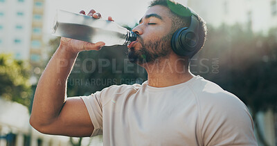 Buy stock photo Fitness, drinking water and man in city with music, break and hydration in training. Athlete, bottle or headphones on run for workout, healthy body or rest on sidewalk with nutrition or care in sport