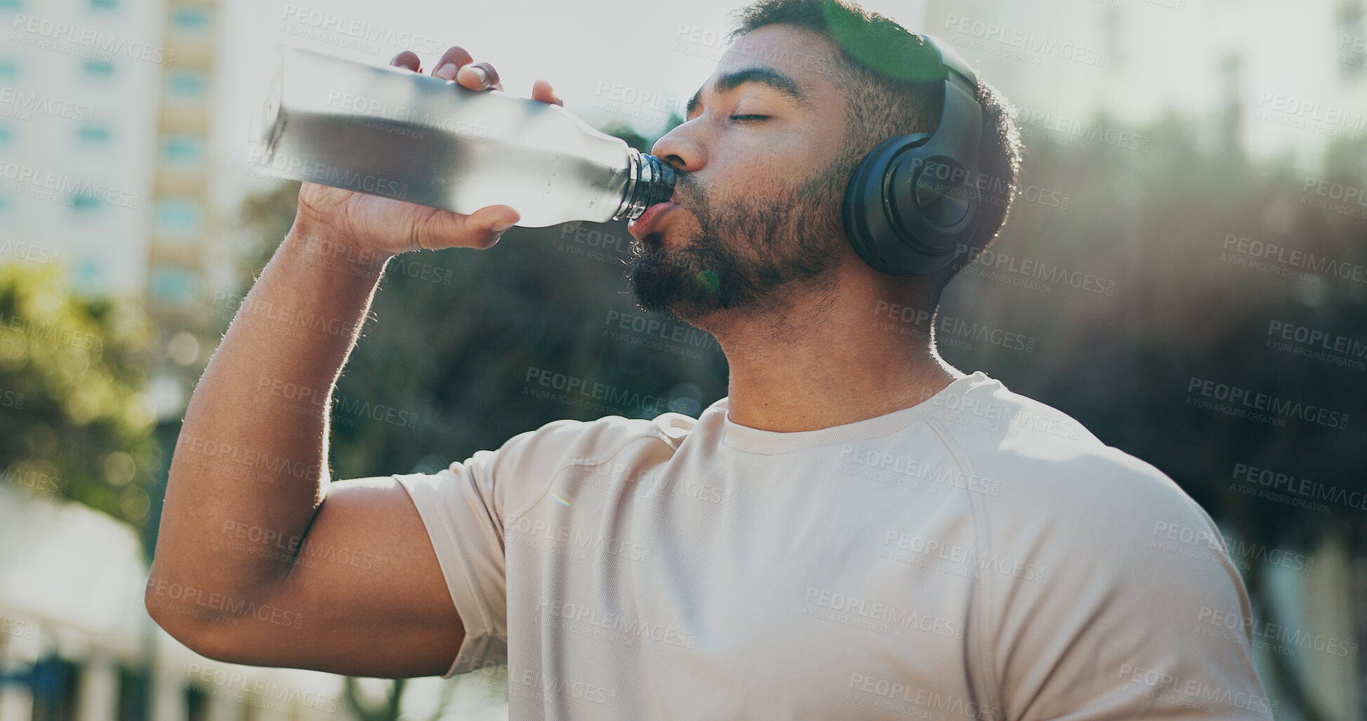 Buy stock photo Fitness, drinking water and man in city with music, break and hydration in training. Athlete, bottle or headphones on run for workout, healthy body or rest on sidewalk with nutrition or care in sport