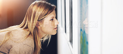 Buy stock photo Shot of a young woman looking at paintings in a gallery