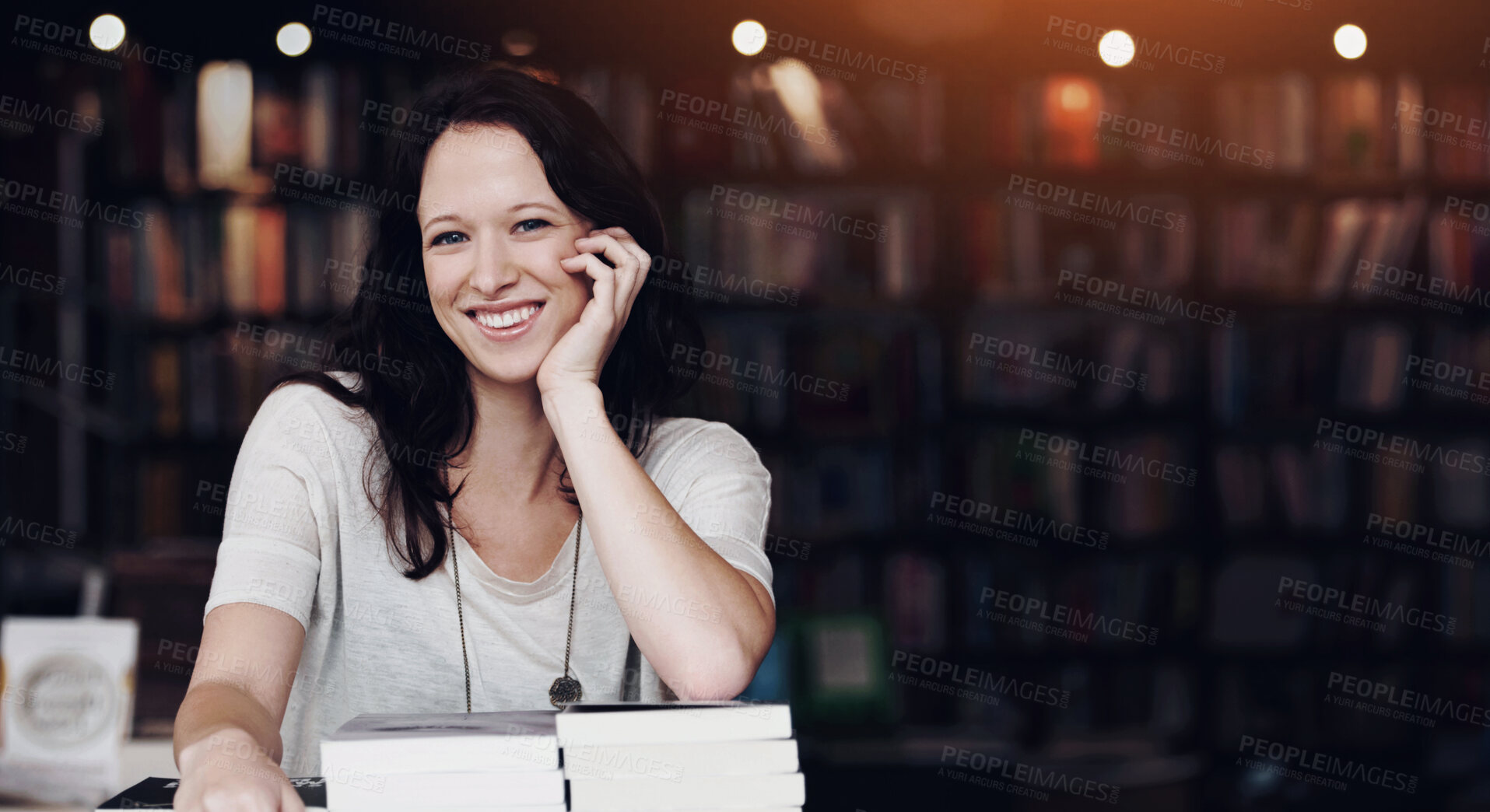 Buy stock photo Portrait of a young woman leaning on stacks of books in a bookstore