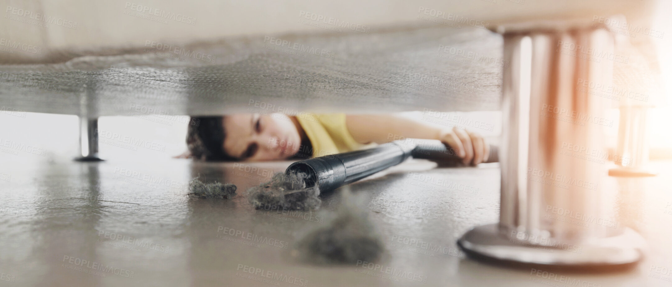 Buy stock photo Young woman reaching under a sofa to get at some dust