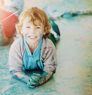 Buy stock photo Portrait, paint and a boy lying on the floor of a studio for creative expression or education at school. Art, painting and an excited young child looking happy with his messy artistic creativity