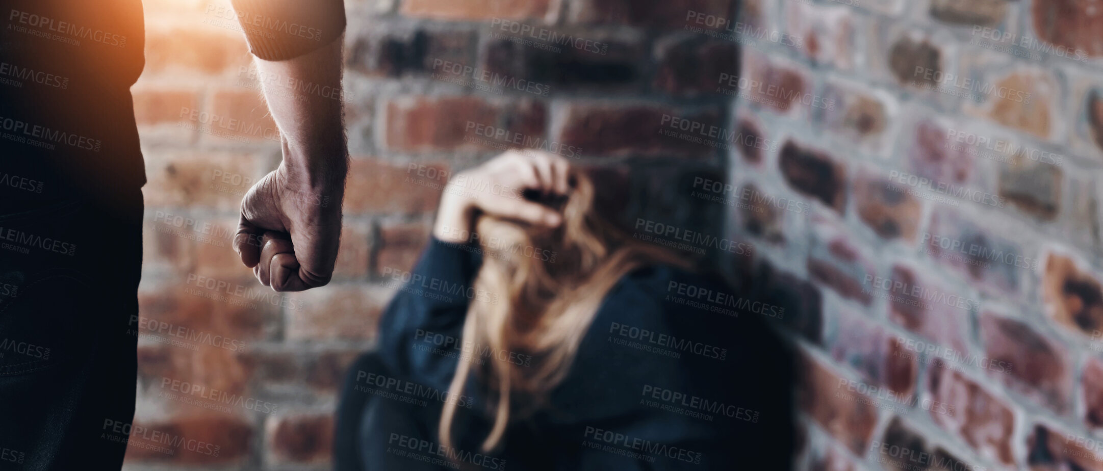 Buy stock photo Abused young woman with her hands in her hair as her abuser stands in front of her