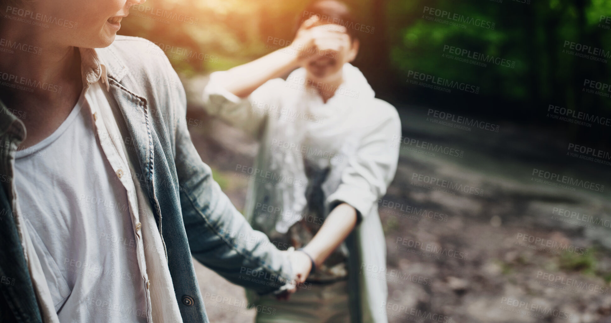 Buy stock photo A girl covering her eyes with her hand is led through the forest by her boyfriend