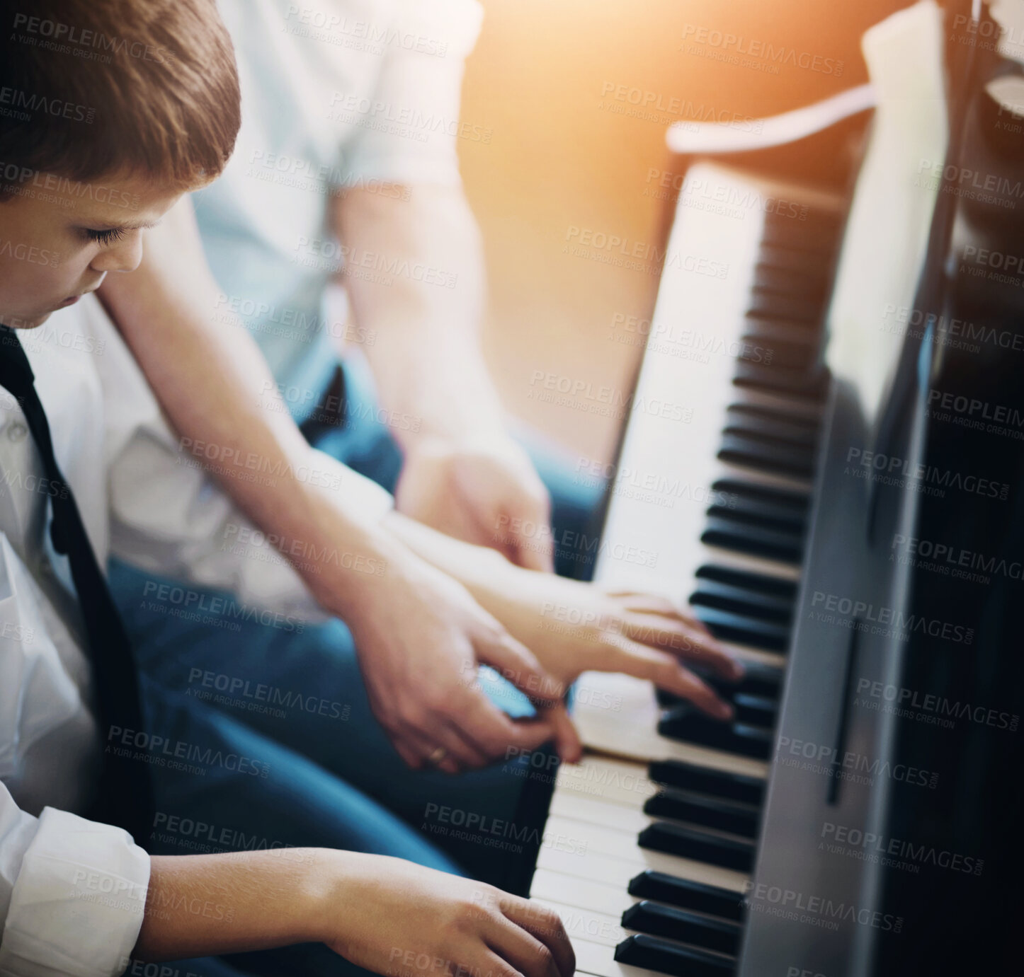 Buy stock photo Young boy playing the piano diligently alongside his tutor - cropped