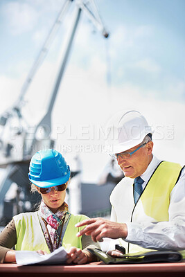 Buy stock photo Two dock workers holding paperwork while standing in the shipyard