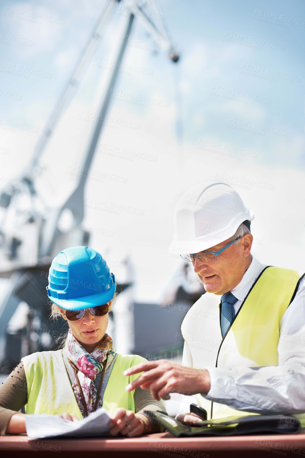 Buy stock photo Two dock workers holding paperwork while standing in the shipyard