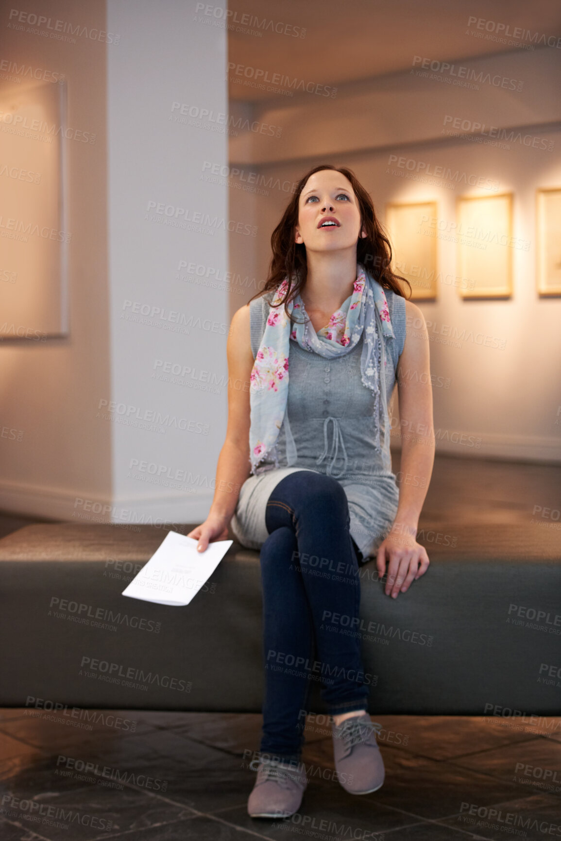 Buy stock photo Shot of a young woman looking at paintings in a gallery