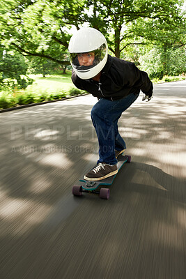 Buy stock photo Shot of a man skateboarding down a lane at high speed on his board