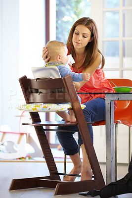 Buy stock photo Woman, baby and food in feeding chair for nutrition, growth and development at table in kitchen of home. Mother, infant and cleaning face after eating, napkin and routine for love, care and nurture